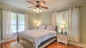 A bedroom with a bed, bedside tables, a ceiling fan, and curtains. - 1/2 Mi to Hot Springs Nat'l Park: Cottage w/ Patio (Hot Springs)