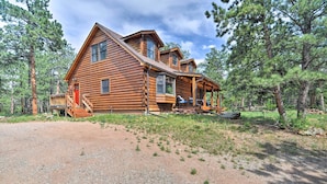 A log cabin with a porch, a covered deck, and a gravel driveway. - The Pinecone Palace w/ Hiking Trail Access! (Lyons)