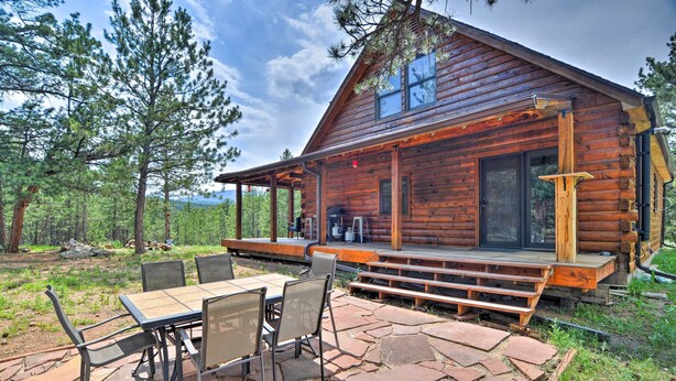 A log cabin with a patio area, outdoor seating, and a view of the surrounding forest. - The Pinecone Palace w/ Hiking Trail Access! (Lyons)
