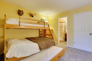 A bunk bed with a wooden headboard, a brown blanket, and a white mattress. There are two wall decorations, one of a bear and one of a moose. A white door is visible to the right. - Walk to Ski Lifts: Keystone Condo w/ Deck & Grill! (Keystone)
