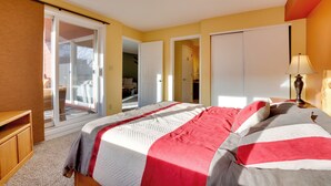 Une chambre à coucher avec un lit, une porte-fenêtre coulissante, une lampe et une table de chevet en bois.