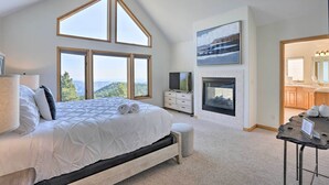 A bedroom with a large bed, a fireplace, and a view of the outdoors. - Spacious Evergreen Home w/ Picturesque Views (Evergreen)