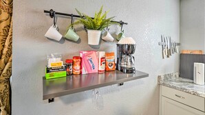 A kitchen with a shelf holding a coffee maker, a potted plant, and various kitchen items. - North Las Vegas Studio w/ Fire Pit: 10 Mi to Strip (North Las Vegas)