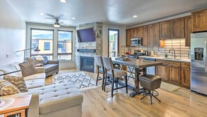 A spacious living room with a fireplace, a dining area, and a kitchen with wooden cabinets and stainless steel appliances. - 3 Mi to Dillon Reservoir: Condo w/ Balcony! (Silverthorne)