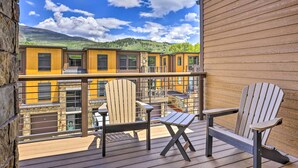 A wooden deck with Adirondack chairs and a view of yellow buildings in the background. - 3 Mi to Dillon Reservoir: Condo w/ Balcony! (Silverthorne)