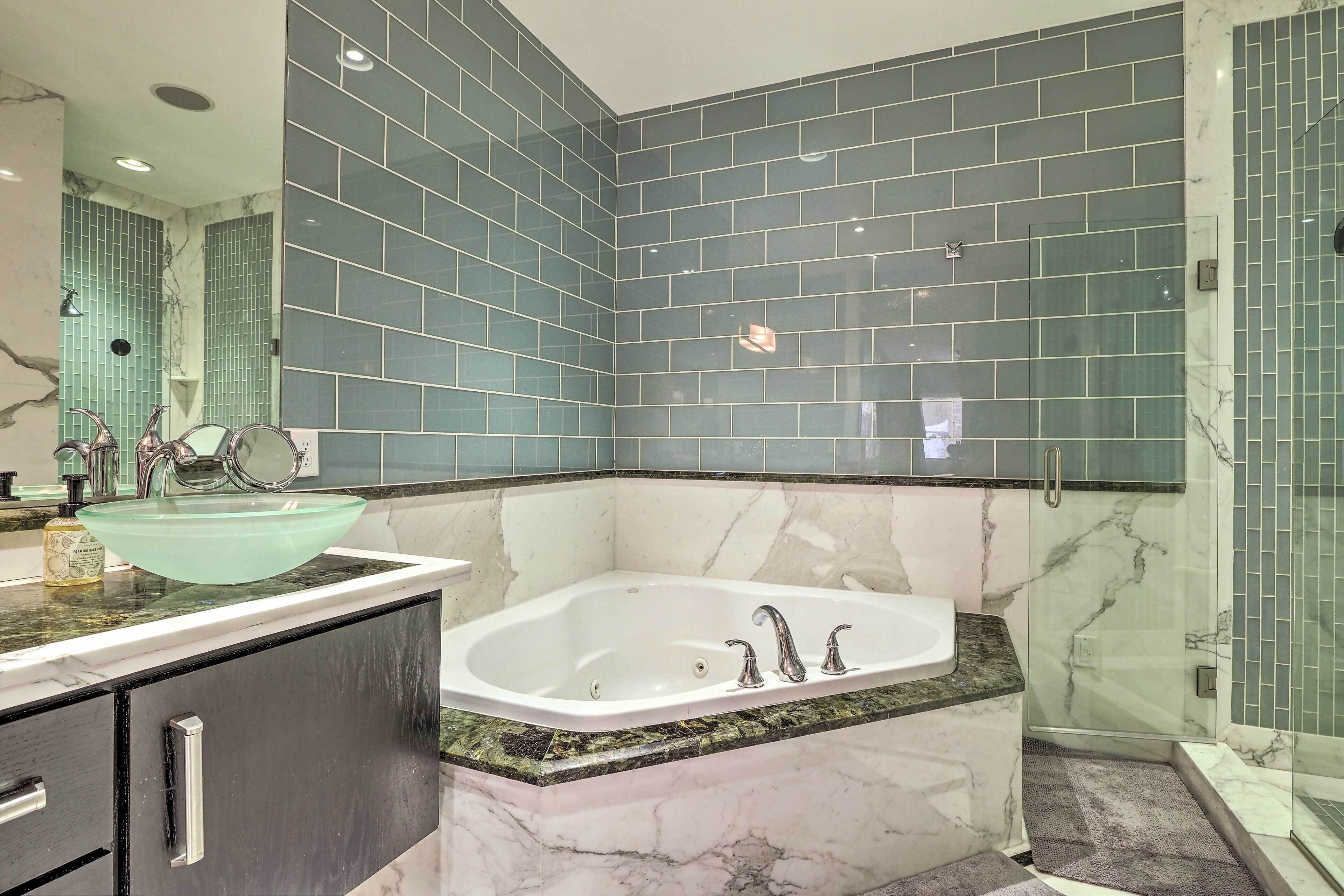 A modern bathroom with a glass-enclosed shower, a freestanding bathtub, and a vanity with a large mirror.