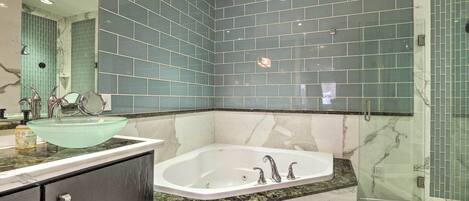 A modern bathroom with a glass-enclosed shower, a freestanding bathtub, and a vanity with a large mirror.