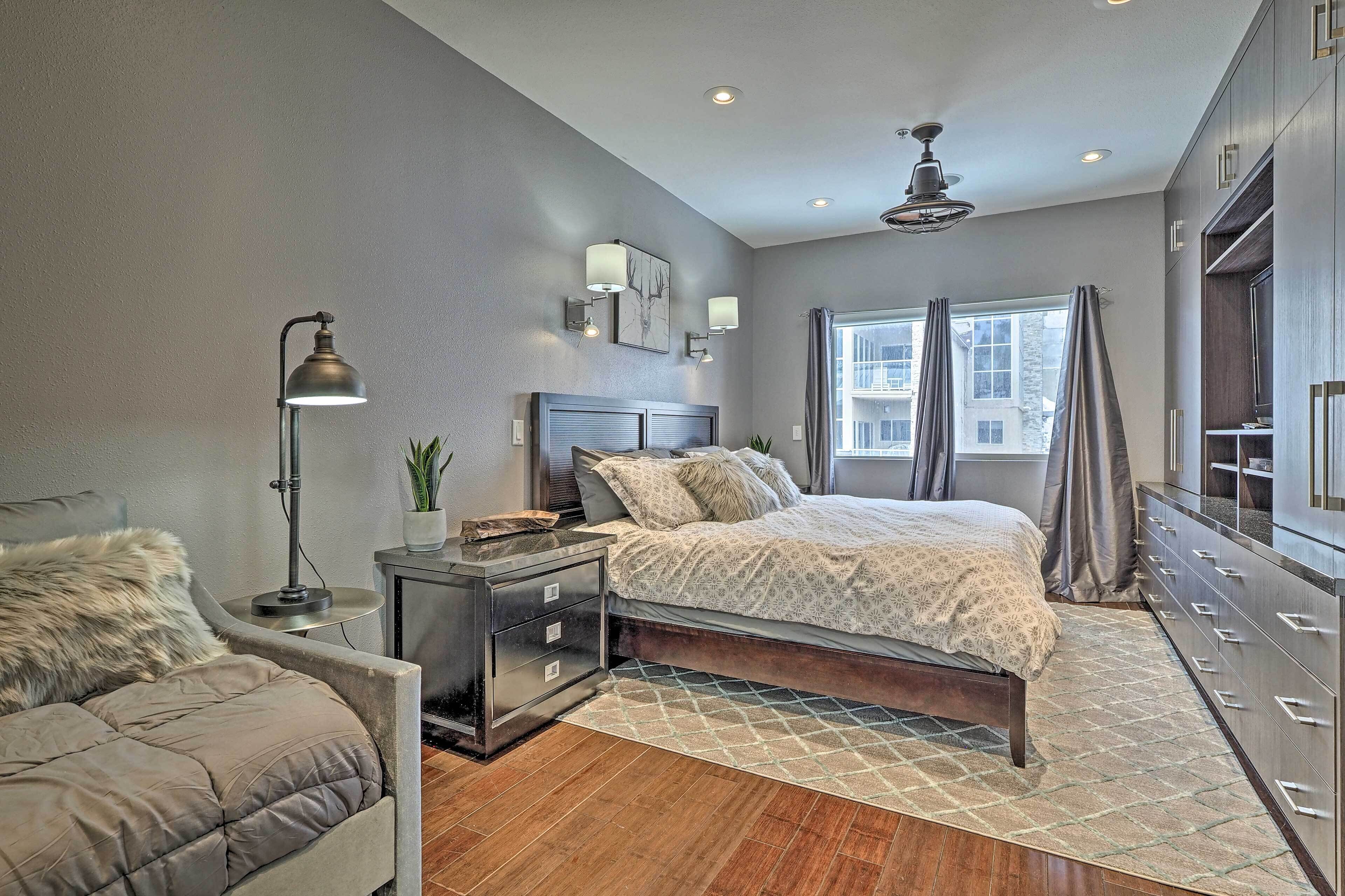 A modern bedroom with a large bed, bedside tables, a desk, and a chair.