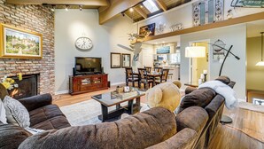A spacious living room with a fireplace, comfortable seating, and a dining area. - Artists Tahoe Retreat: Pool, Art & Ski Access! (Incline Village)
