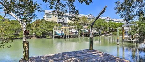 A wooden dock extending into calm water with boats docked nearby.