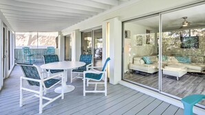 Ein Außenbereich mit Terrasse, einer weißen Decke, einem runden Tisch und blauen Stühlen.