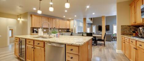 A spacious kitchen with wooden cabinets, a granite countertop, and a central island with a sink.