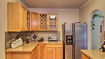 A kitchen with wooden cabinets, a stainless steel refrigerator, a toaster, and a decorative plant.