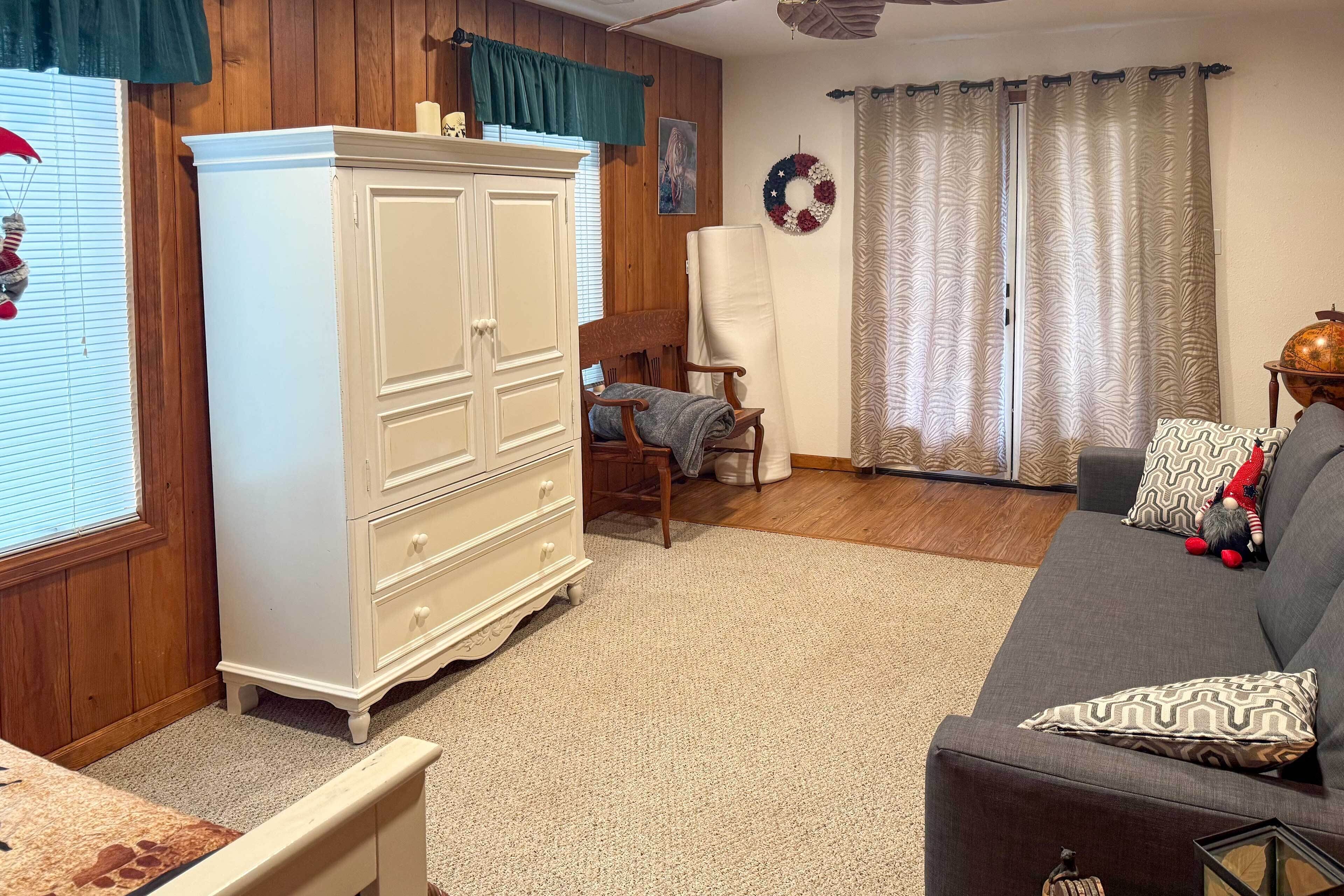 Una sala de estar con un aparador blanco, un sofá gris y una silla de madera.