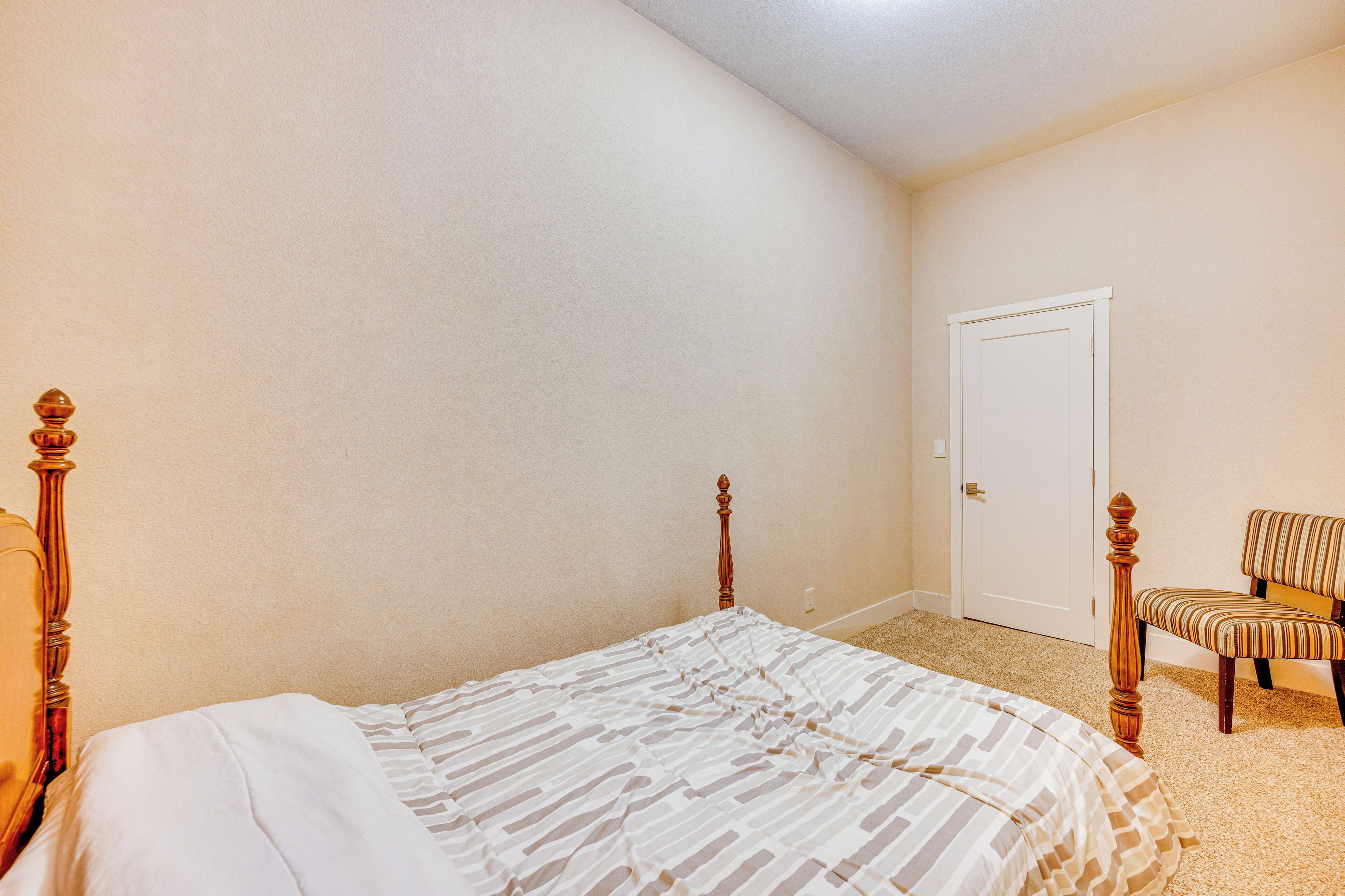 A bedroom with a bed, a chair, and a door.