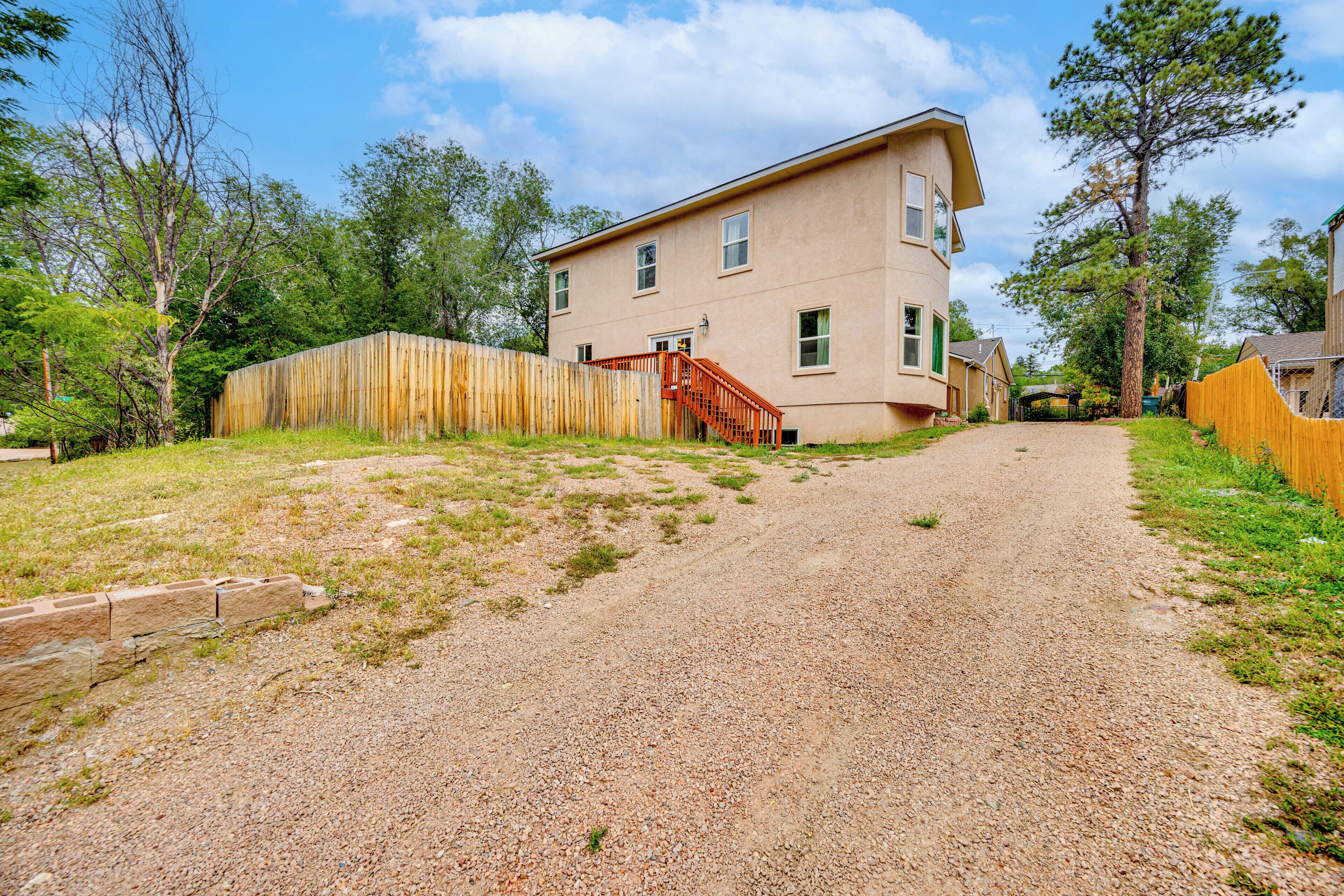 A two-story house with a gravel driveway and a wooden fence.