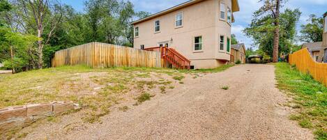 A two-story house with a gravel driveway and a wooden fence.