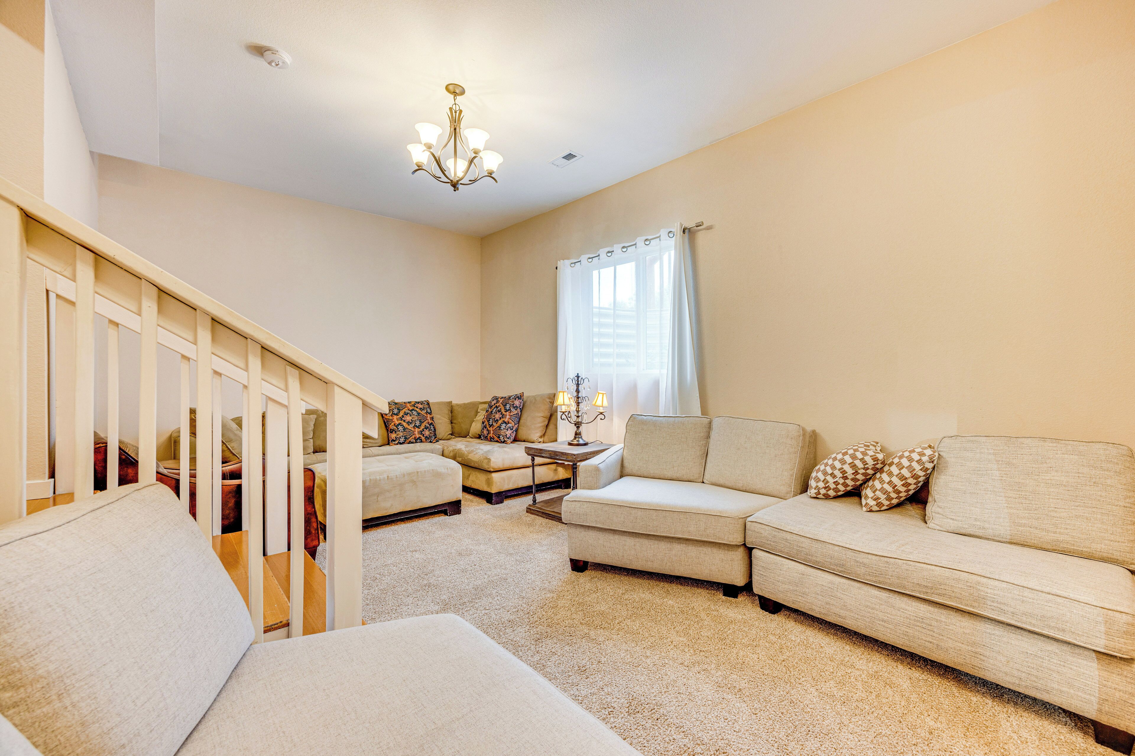 A living room with a staircase, a sofa set, and a chandelier.