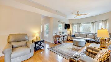 A spacious living room with a leather sofa, a coffee table, and a TV mounted on the wall.