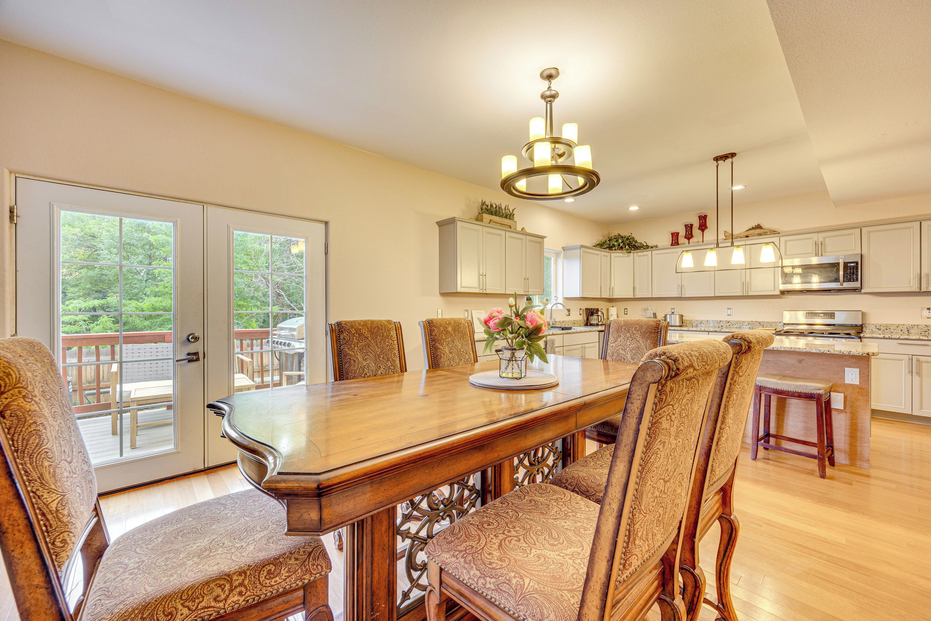 A spacious kitchen with a large dining table, chairs, and a chandelier.