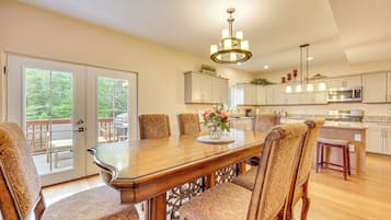 A spacious kitchen with a large dining table, chairs, and a chandelier.