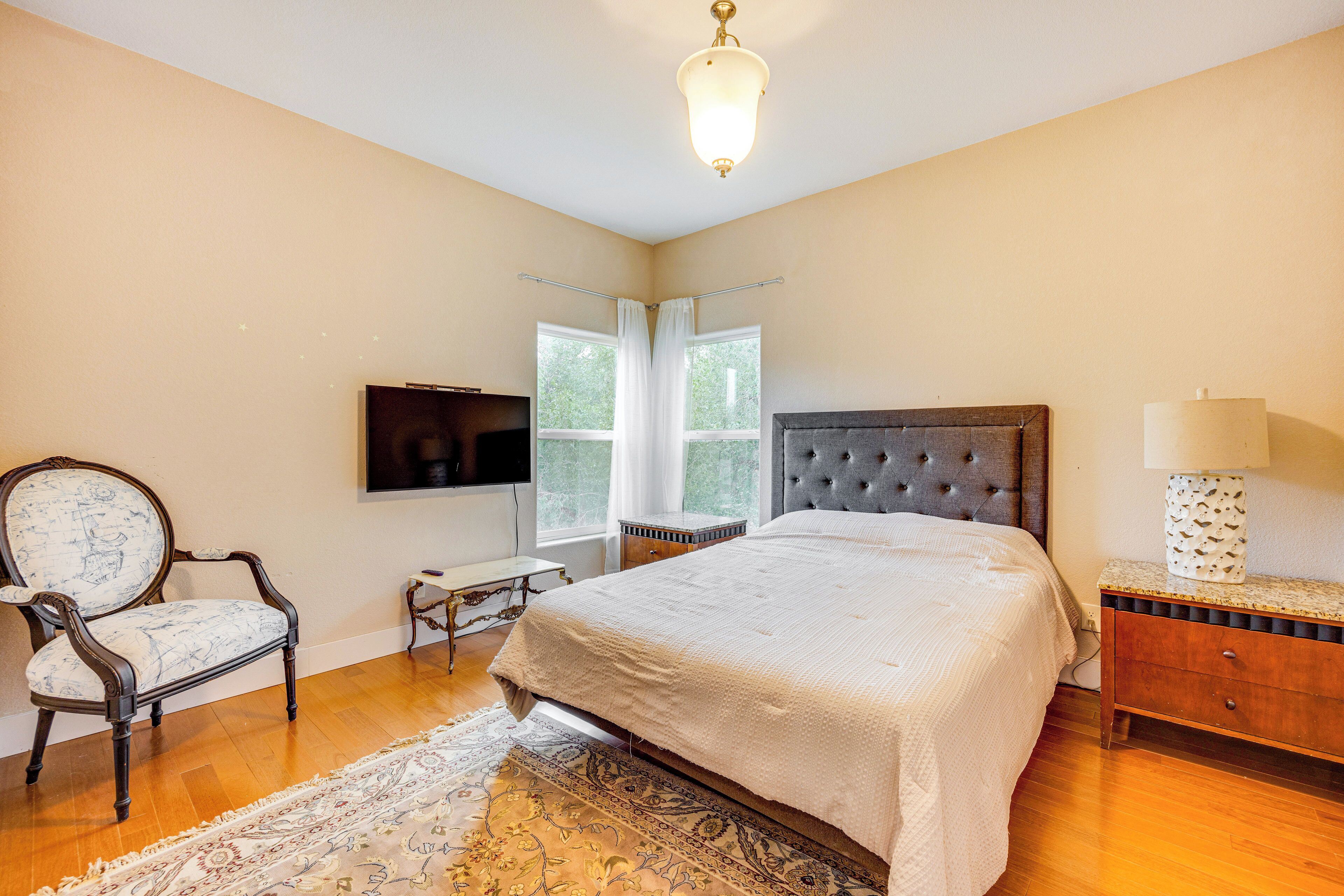 Une chambre avec un grand lit, une chaise, une télévision et une lampe.