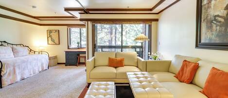 Un amplio salón con sofá, reposapiés y cama.