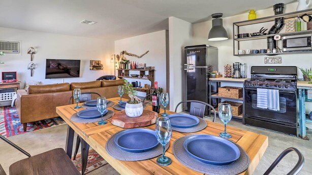 A modern kitchen with a built-in oven, a refrigerator, and a dining area set with blue plates and glasses.