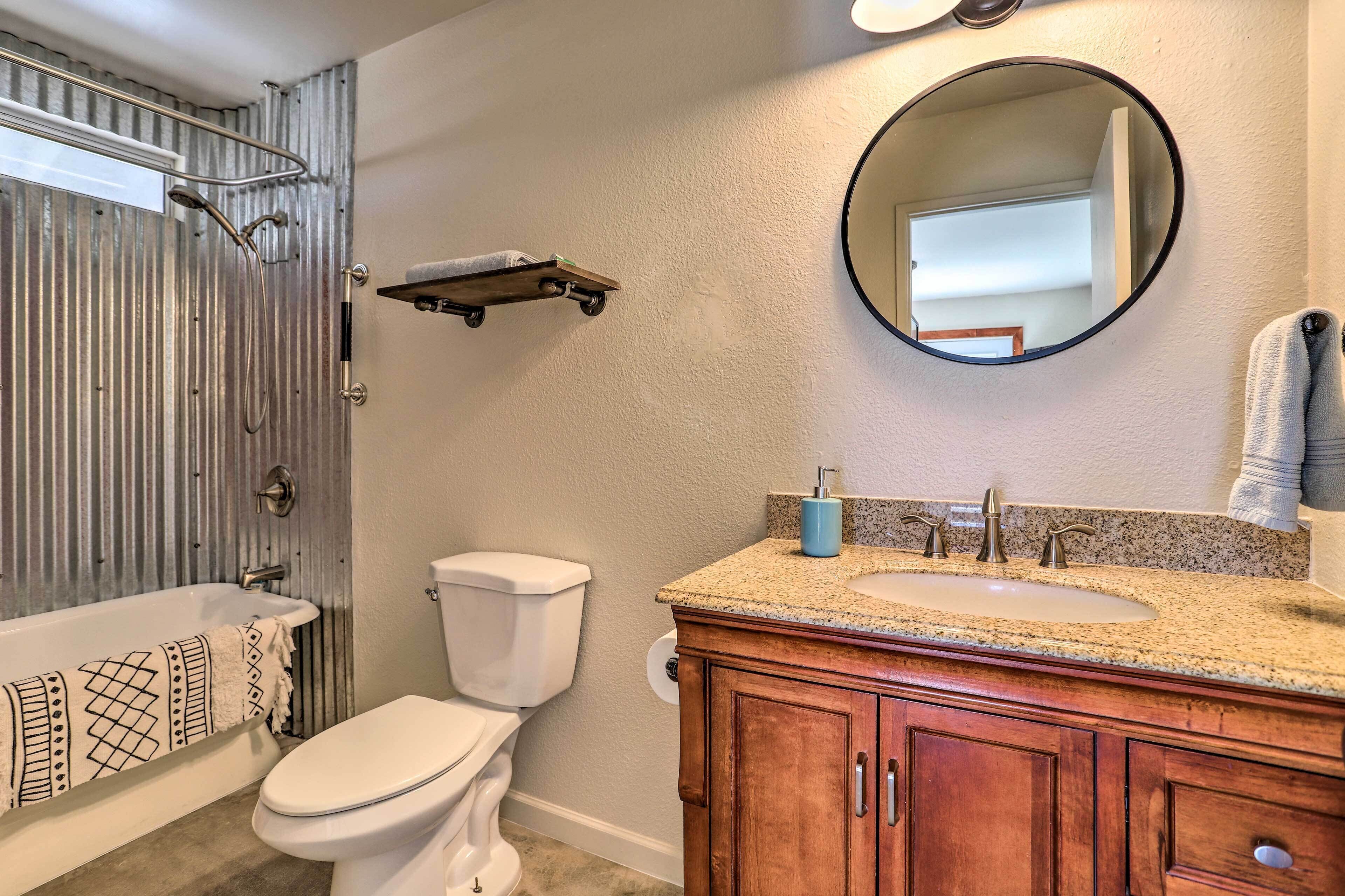 A bathroom with a bathtub, toilet, vanity with a sink, and a mirror.