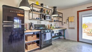 A modern kitchen with a Galanz refrigerator, a stove, a microwave, and wooden shelves.
