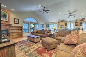 A spacious living room with a fireplace, comfortable seating, and a kitchen area.