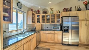 Una cocina moderna con armarios de madera, un refrigerador de acero inoxidable y una ventana que ofrece luz natural.