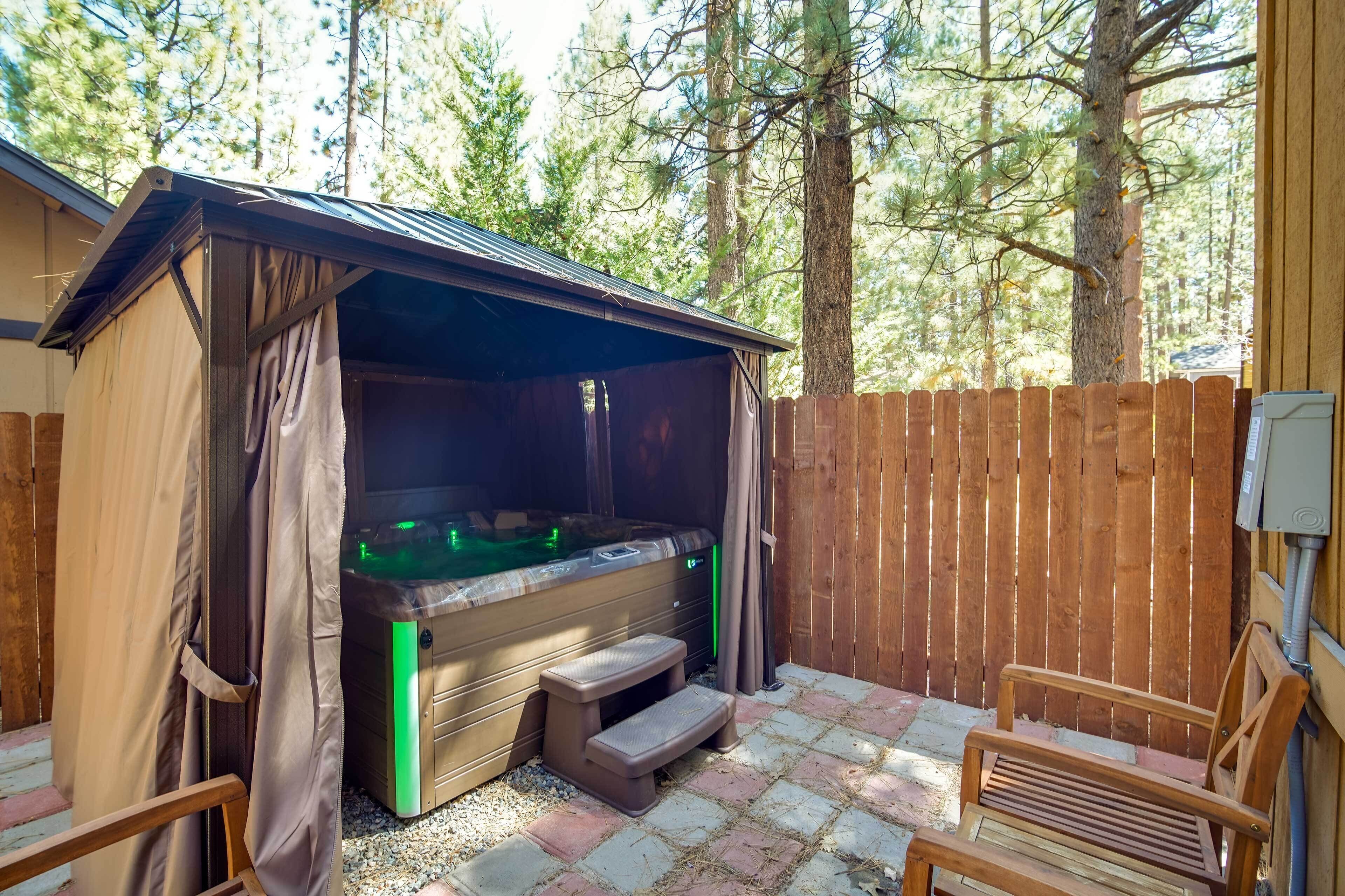 A hot tub with steps, surrounded by a wooden fence and trees.