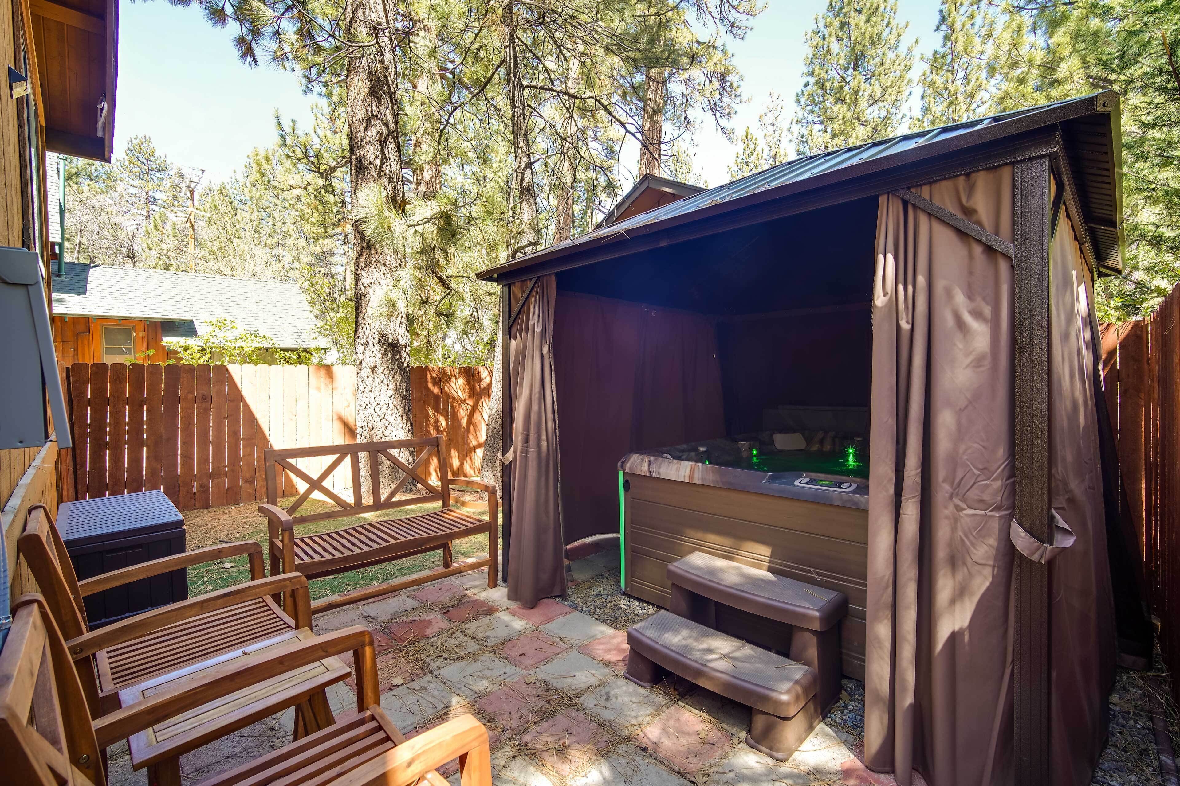 A wooden deck with outdoor seating, a hot tub, and a covered area with curtains.