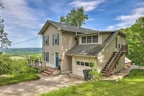 A two-story house with a front porch, a staircase, and a garage. - Spectacular Views w/ Deck, Fire Pit, & Game Room! (Keuka Park)