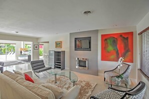 A modern living room with a glass coffee table, leather sofa, and a fireplace. - Upscale Wilton Manors Retreat, 2 Mi From Ocean! (Wilton Manors)