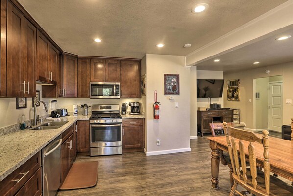 Una cocina con armarios de madera, electrodomésticos de acero inoxidable y una zona de comedor con mesa y sillas de madera.