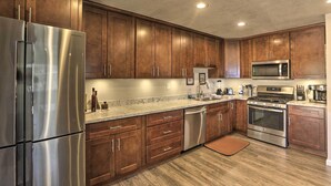 Una cocina moderna con electrodomésticos de acero inoxidable, armarios de madera y encimeras de granito, y un horno empotrado.