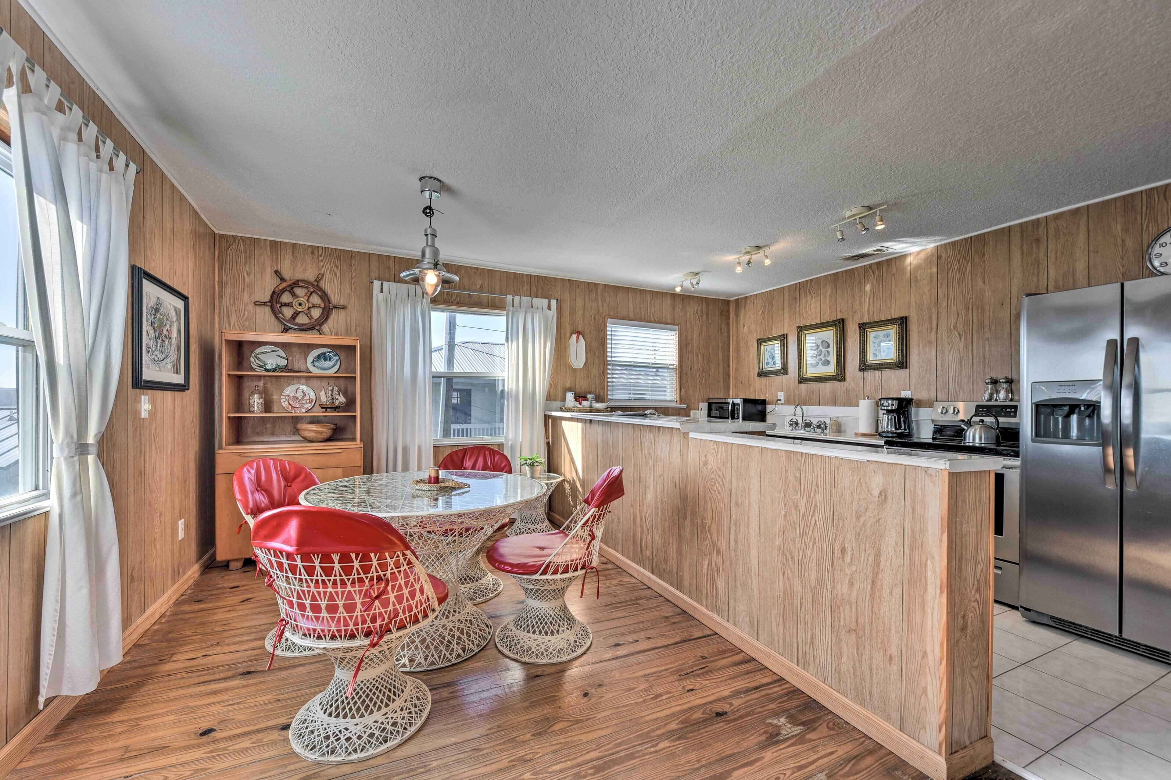 A kitchen with a wooden island, stainless steel appliances, and a dining area with wicker chairs and a table.