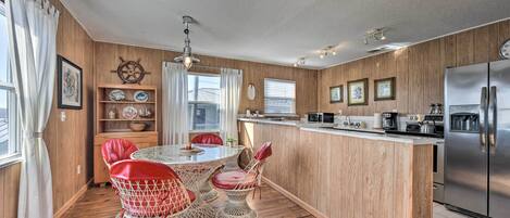 A kitchen with a wooden island, stainless steel appliances, and a dining area with wicker chairs and a table.