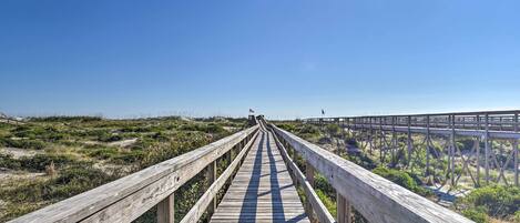 A wooden boardwalk leading to a beach with a clear sky.