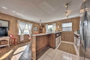 Una cocina compacta con paredes de madera, una isla central y un refrigerador.