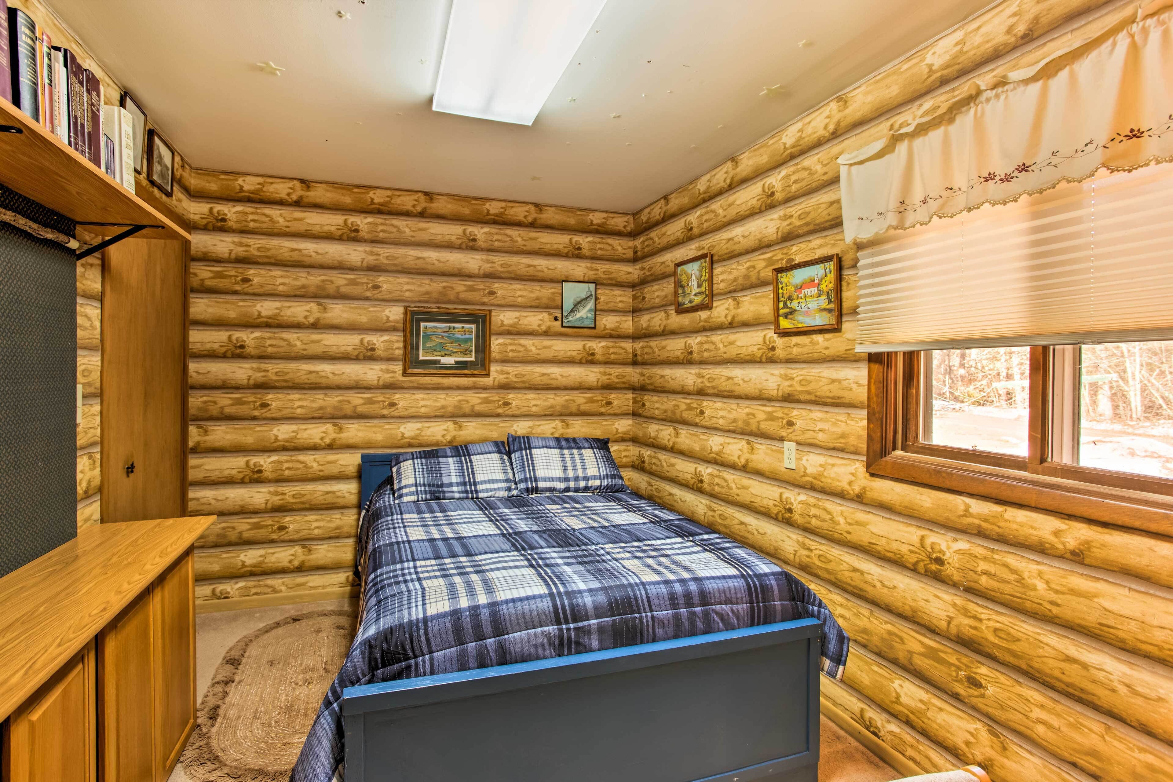 Une chambre dans une cabane en rondins, avec un lit, une bibliothèque et des tableaux encadrés accrochés aux murs.