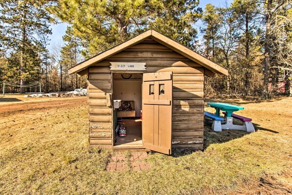 A wooden cabin with a sign reading "Dizzy Land" and a picnic table nearby.
