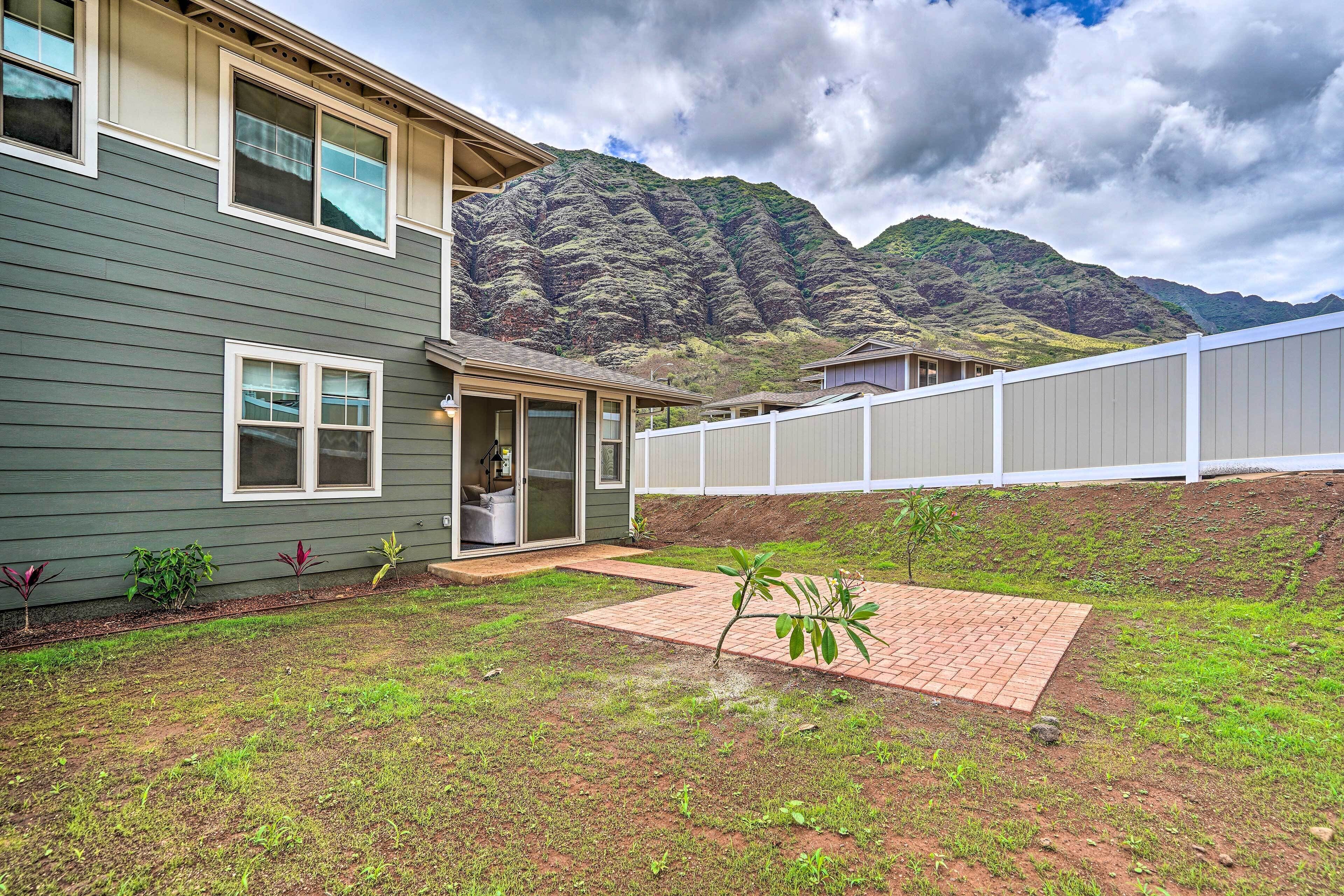 A house with a backyard, a brick patio, and a mountain backdrop.