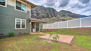 A house with a backyard, a brick patio, and a mountain backdrop.