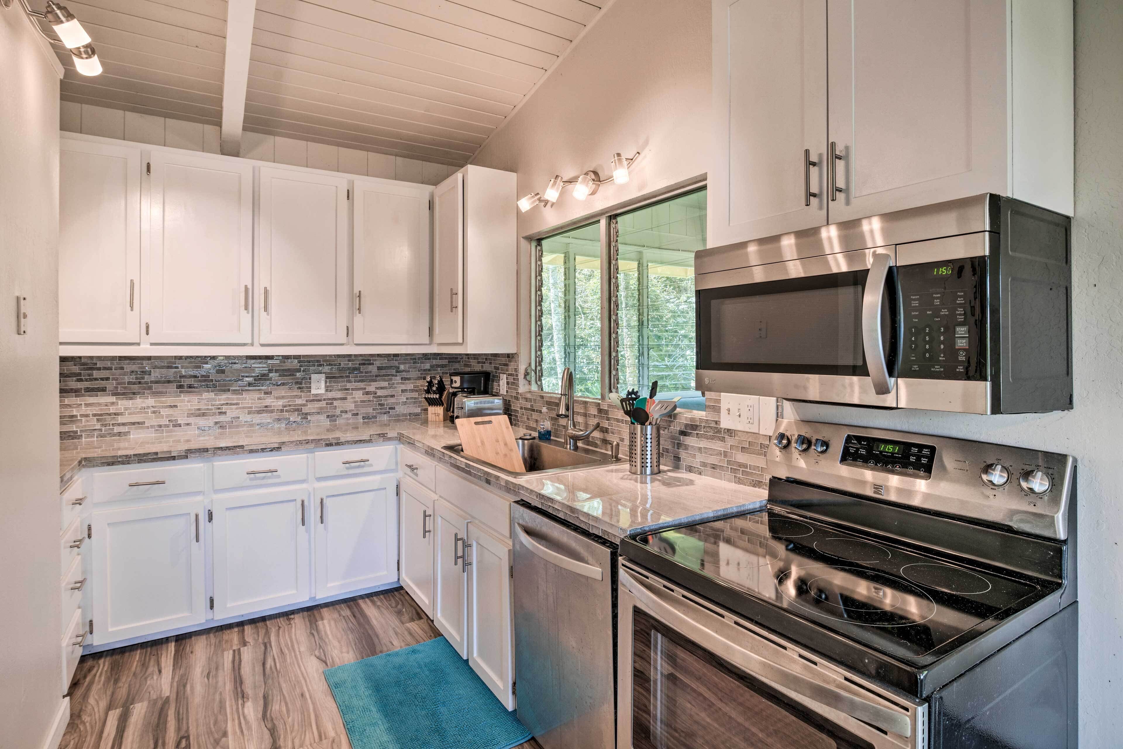 A modern kitchen with white cabinets, a stainless steel oven, and a microwave.