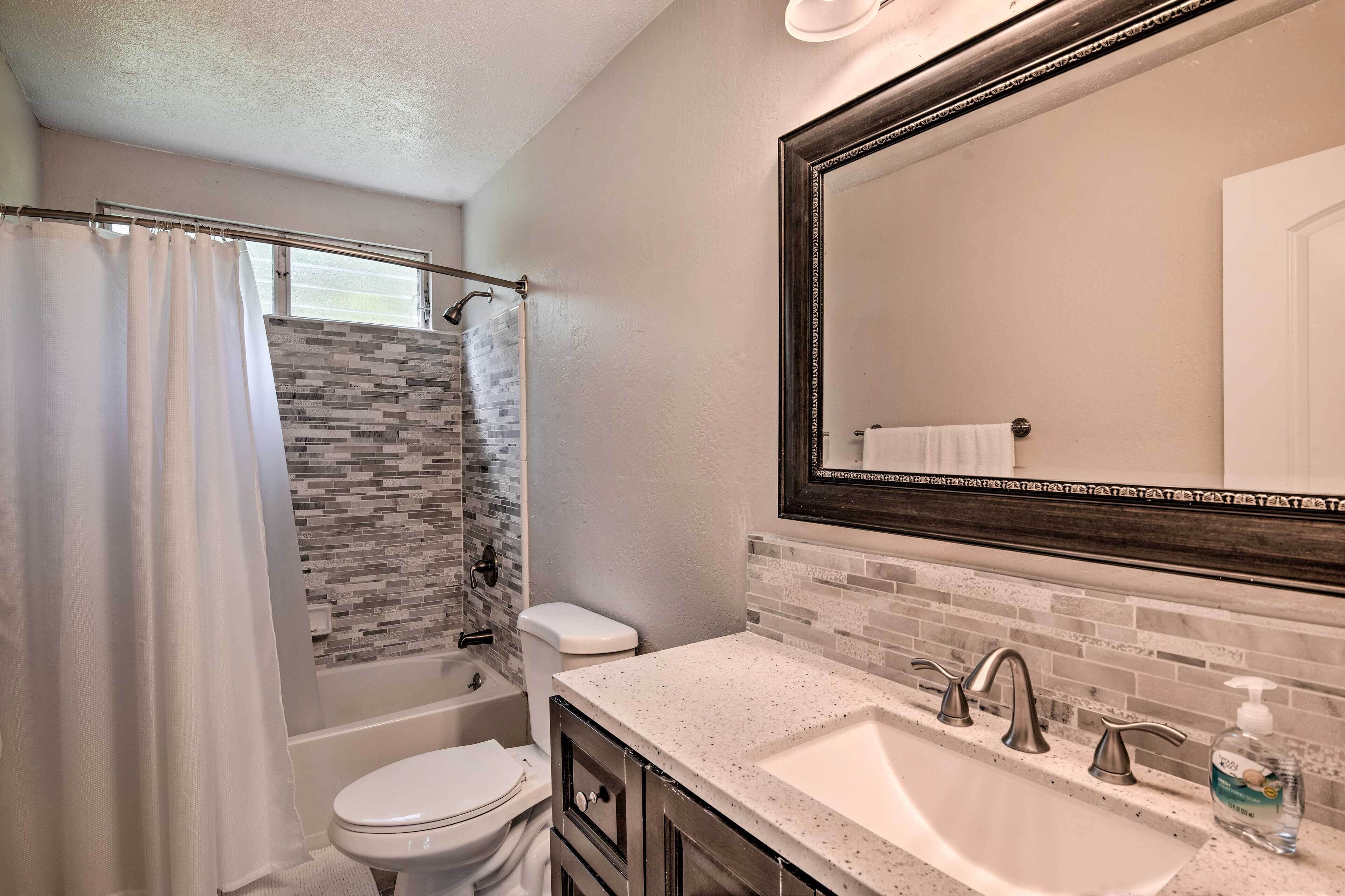 Une salle de bain équipée d’une douche, de toilettes, d’un lavabo et d’un grand miroir.