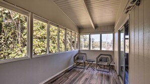 Un solárium con amplias ventanas, dos sillones y una mesita.