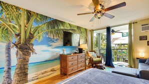 A bedroom with a beach mural, a ceiling fan, a bed, a dresser, and a view of the outdoors. - Tropical Kailua-kona Escape < 7 Mi to Keauhou Bay! (Kailua-Kona)